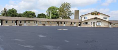 A motel with a large parking lot, a single-story building, and a sign reading 'Budget Inn.'