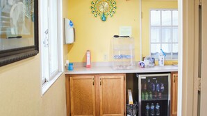 A kitchen with wooden cabinets, a refrigerator, a microwave, and a window. - The Perrysburg Budget Inn (Perrysburg)