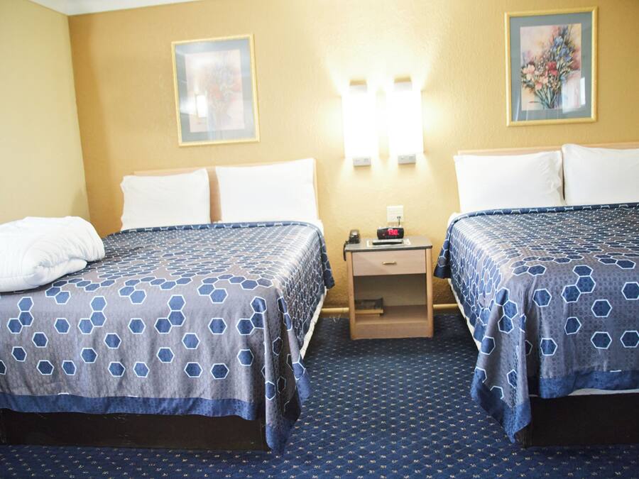 Une chambre d’hôtel avec deux lits, une table de chevet et une lampe fixée au mur.