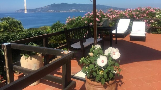 A terrace with a view of the sea, a wooden bench, a table, and a potted plant. - Villa with swimming pool and views of the Argentario. WiFi free (Ansedonia)