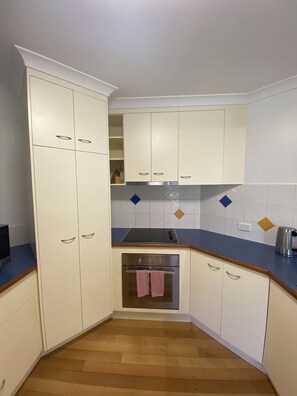A kitchen with white cabinets, a stainless steel oven, and a blue countertop.