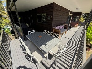 An outdoor deck with a table and chairs, a wooden bench, and a covered barbecue area. - Merindah - Pet-Friendly, Coastal Living at its Best (Agnes Water)