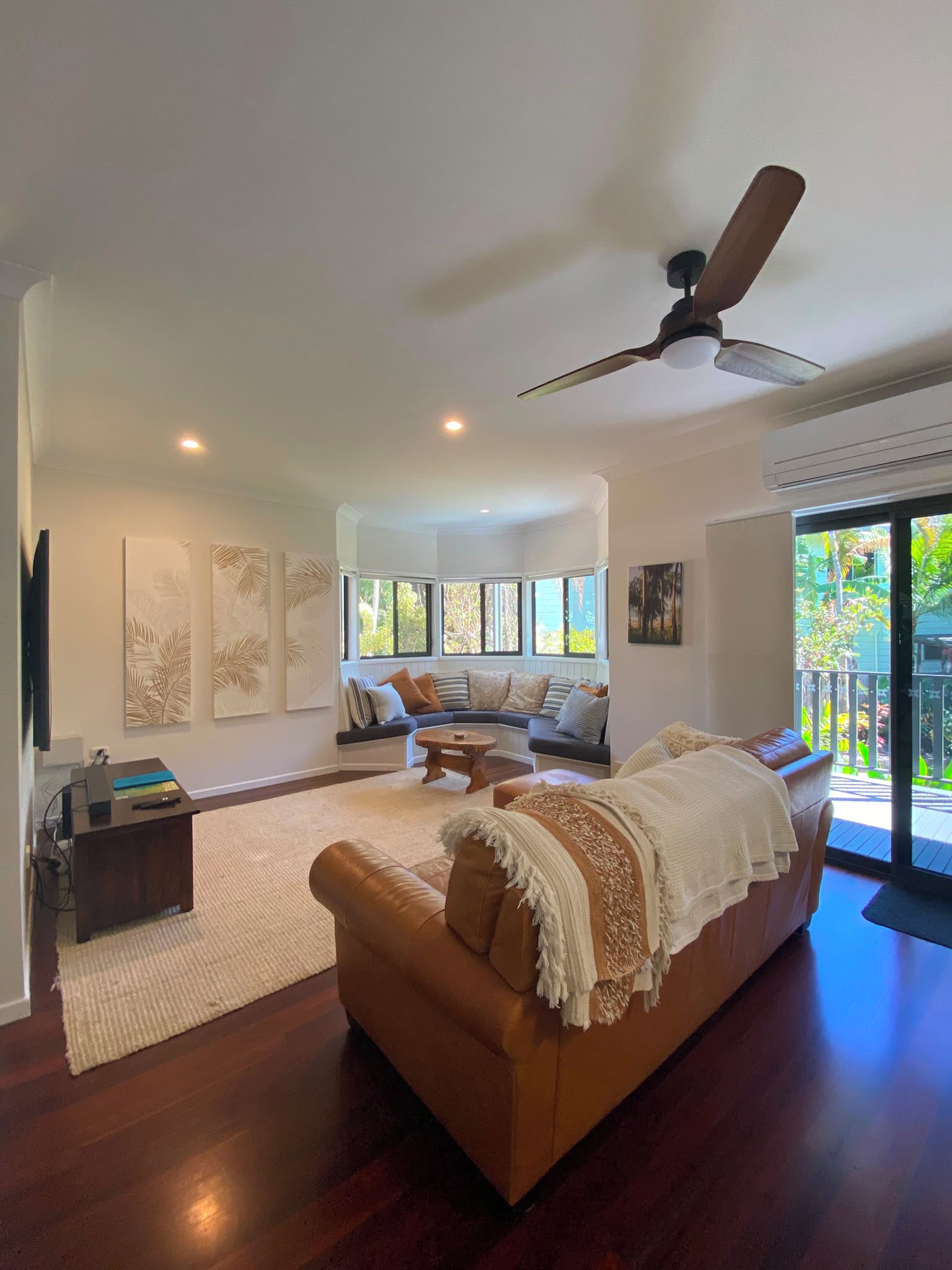 A spacious living room with a large sofa, a coffee table, and a ceiling fan.