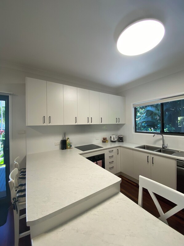 Una cocina moderna con armarios blancos, una isla central y un ventanal con vistas a zonas verdes.