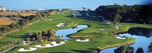 A golf course with water hazards, sand bunkers, and a view of the ocean.