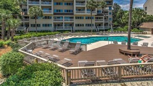 A hotel with a pool area, multiple balconies, and lush greenery.