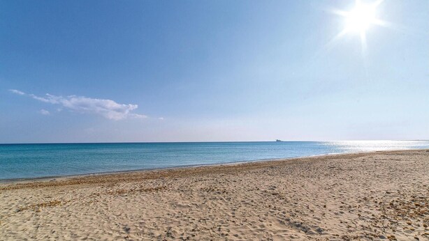 Une plage avec un ciel dégagé et une eau calme.