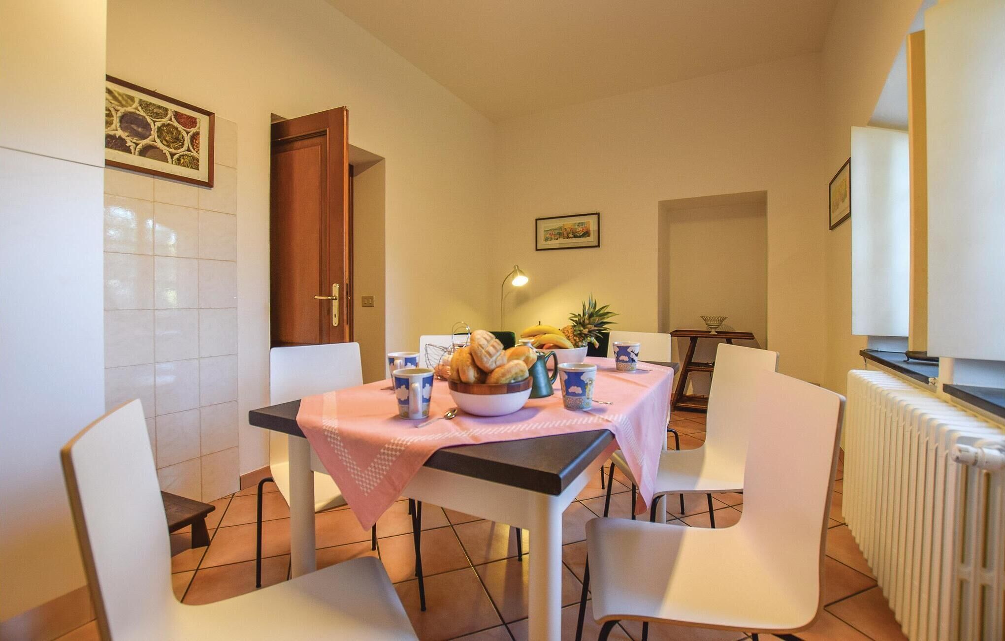 A dining area with a table set for four, a bowl of bread, a pineapple, and a coffee pot.
