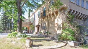 Un bâtiment rustique en pierre, doté de fenêtres en arc de cercle et d’un chemin en briques menant à l’entrée.