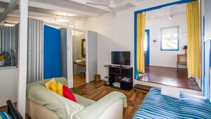 A room with a sofa, a bed, a TV, and a mirror. - Sunset Villa • Pet-Friendly Studio with Ocean Views in Beautiful 1770 (1770)