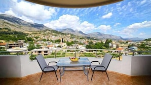 A balcony with a table and chairs, overlooking a mountainous landscape with a town below. - Villas metoxi (Heraklion)