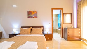 A hotel room with a large bed, two bedside tables with lamps, a dresser, and a painting on the wall. - Villas metoxi (Heraklion)