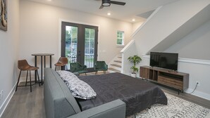 Een moderne slaapkamer met een bed, een televisie, een plafondventilator en een trap naar een hoger niveau.