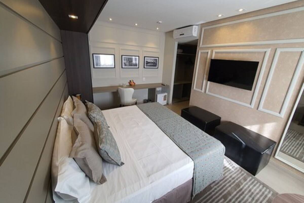 Una habitación de hotel moderna con una cama grande, un escritorio, un televisor y un armario.