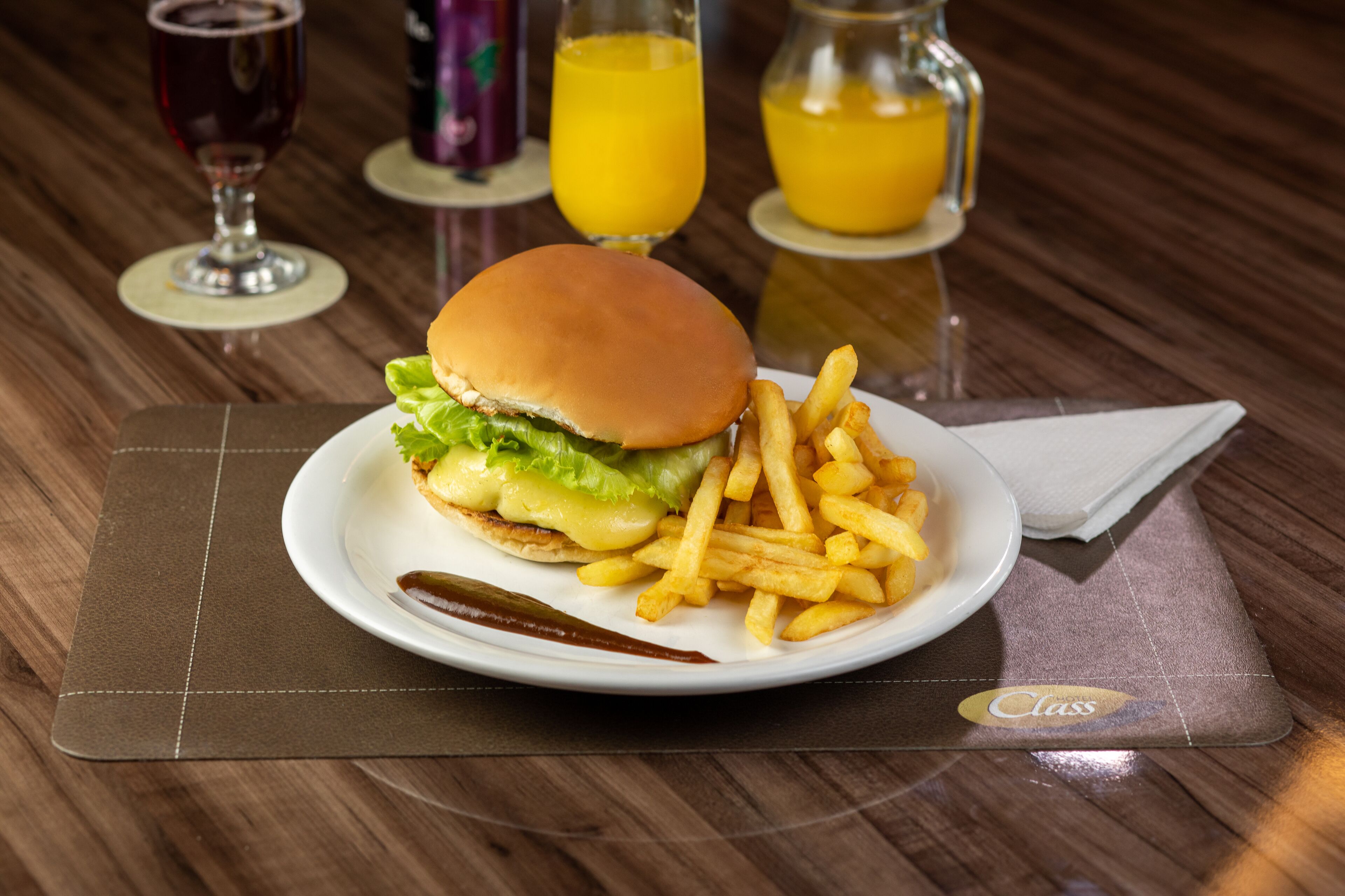 A plate with a burger and fries on a table with a placemat.