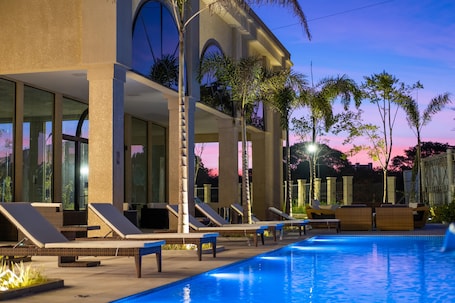Una piscina al aire libre, sillones reclinables de piscina