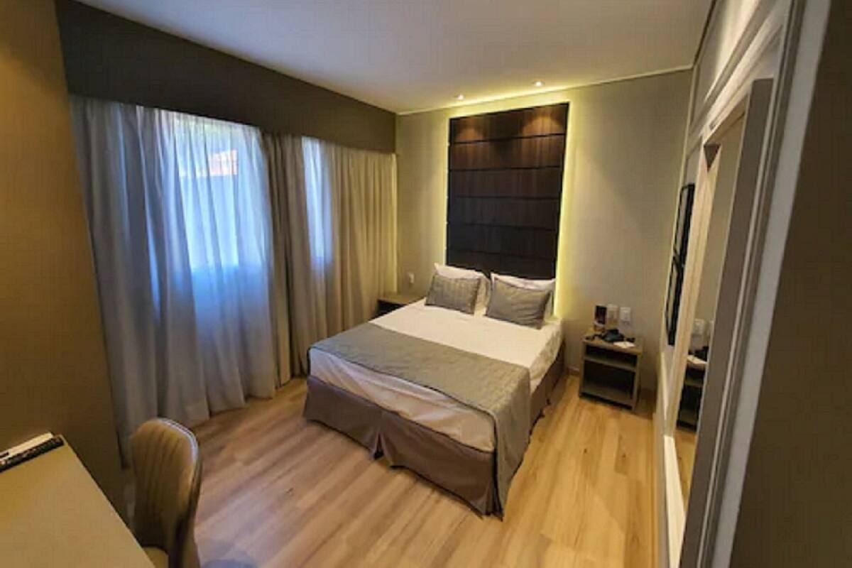 Una habitación de hotel moderna con una cama grande, un escritorio y una silla.
