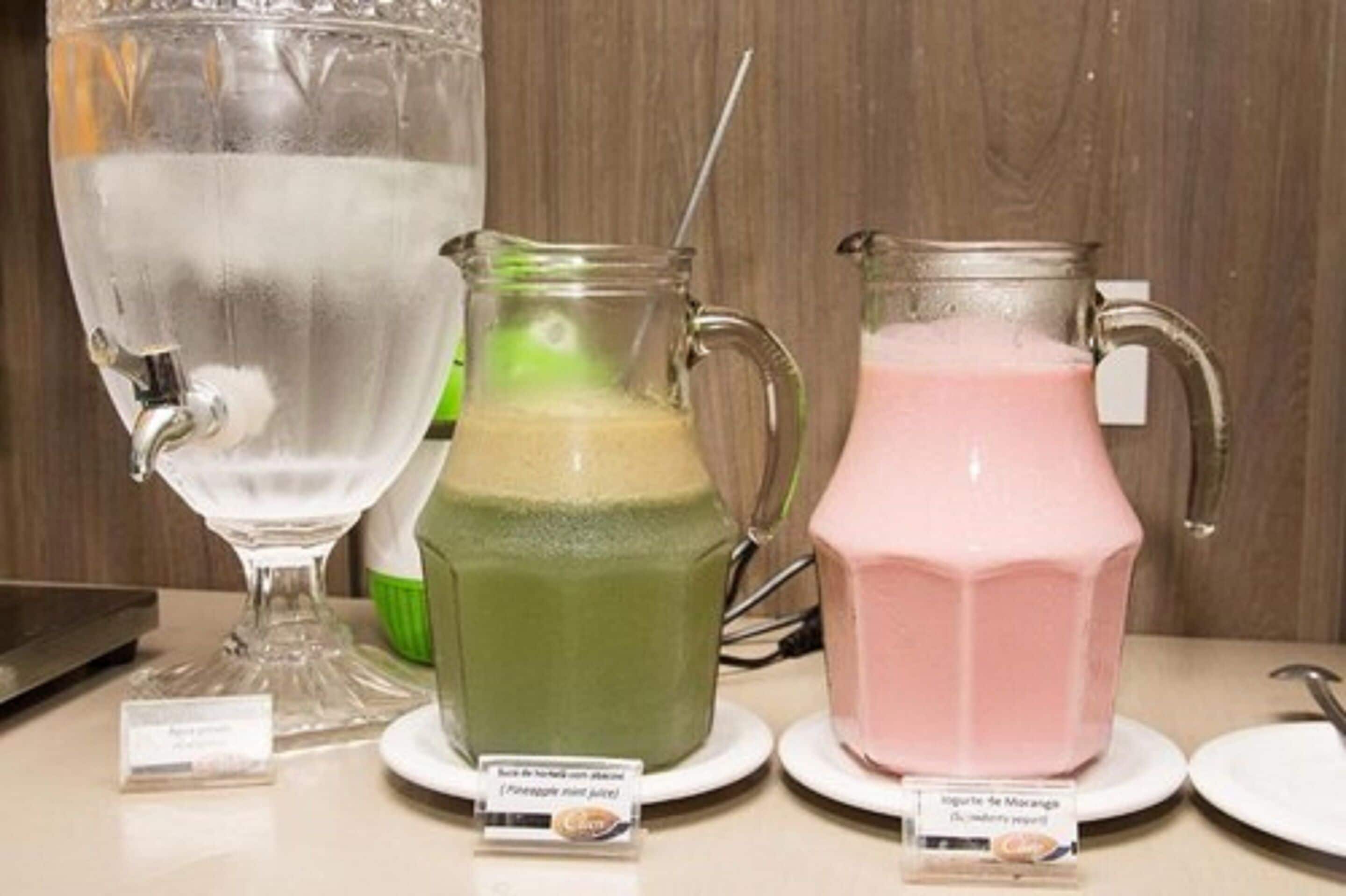 Three pitchers of different colored beverages on a table with labels.