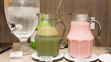 Three pitchers of different colored beverages on a table with labels.