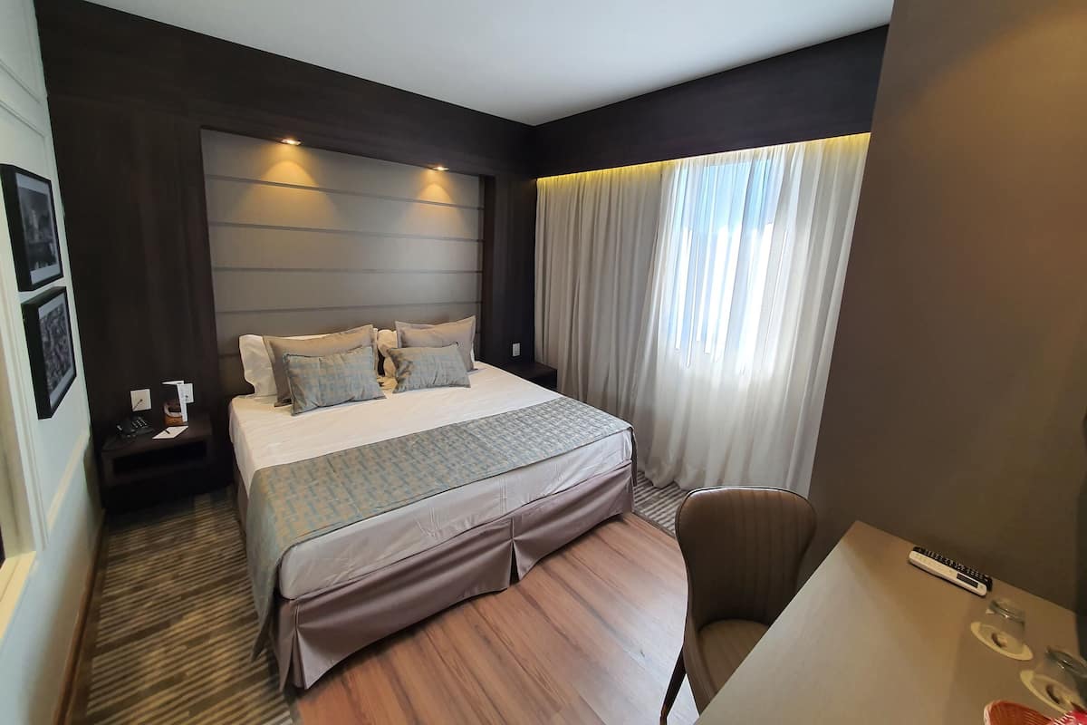 Una habitación de hotel moderna con una cama grande, un escritorio y una silla.