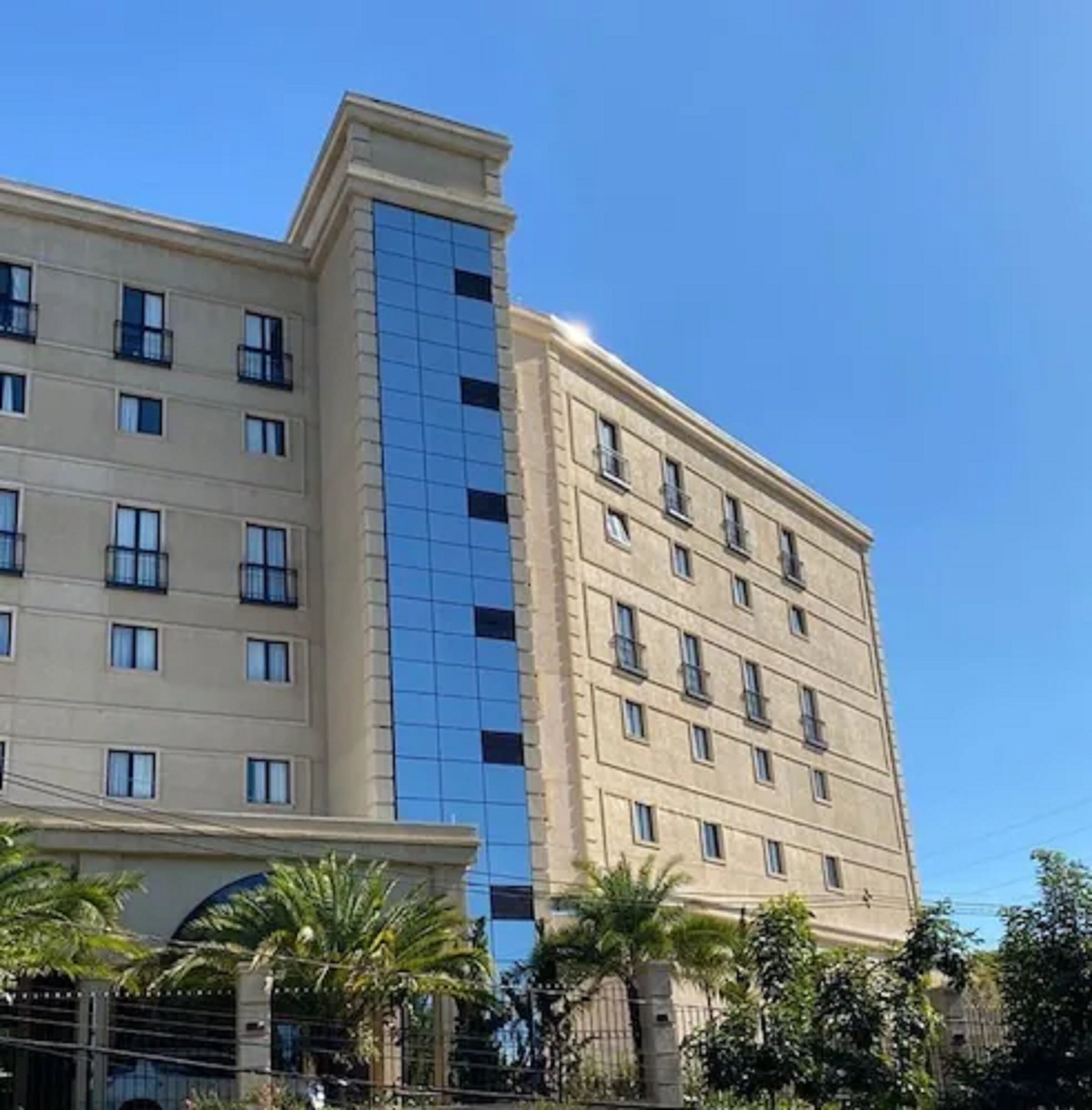 Ein mehrstöckiges Hotel mit moderner Fassade, das Glas und Beige im äußeren Erscheinungsbild kombiniert.