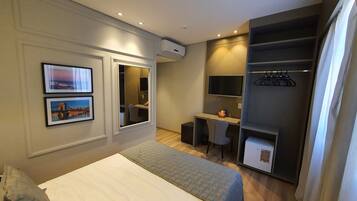 Una habitación de hotel con cama, escritorio, silla, armario y televisor.