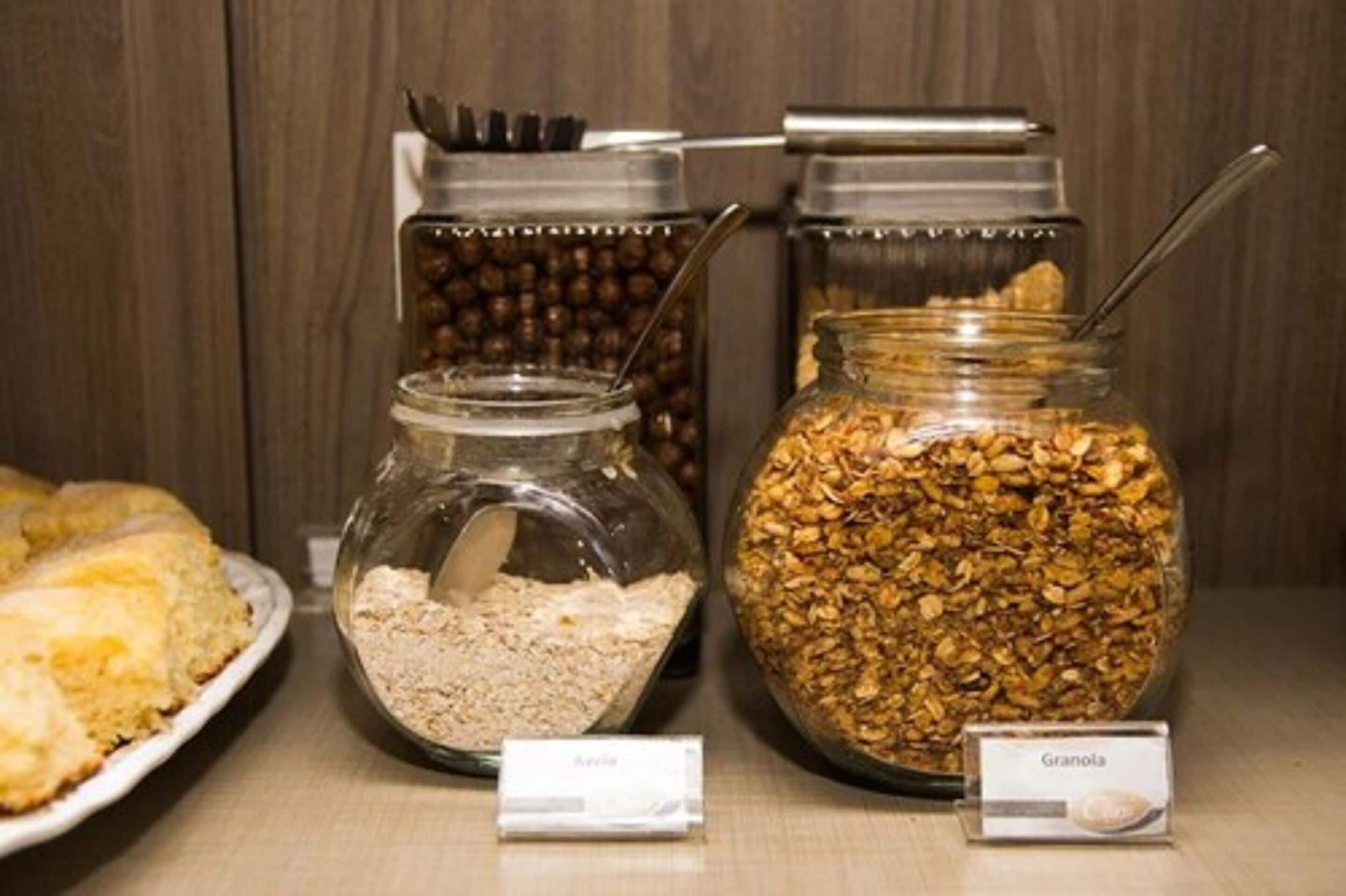 A food display with jars labeled "Avena" and "Granola," and a plate of biscuits.