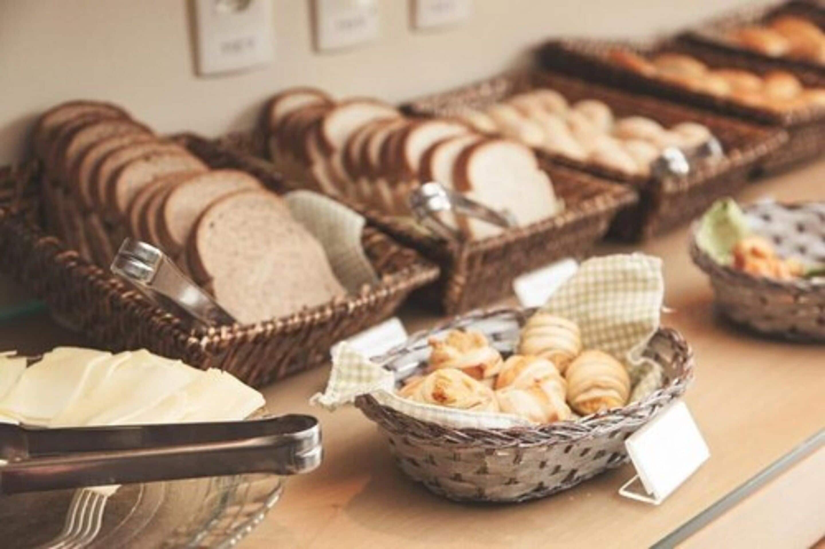 A buffet with various bread and pastries displayed in baskets.