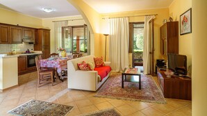 Una sala de estar con sofá, televisión y comedor con mesa y sillas.