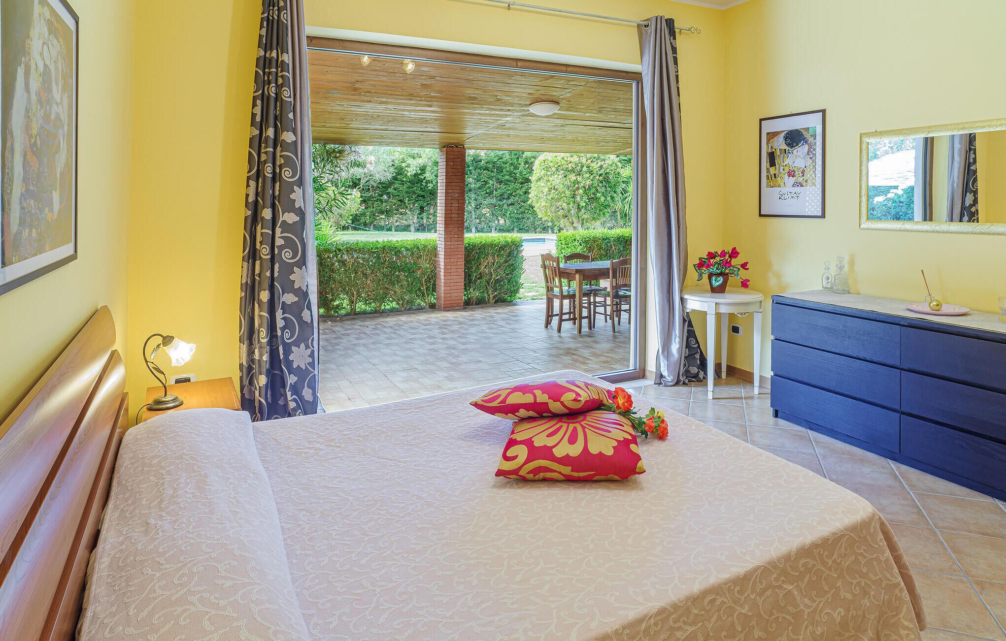 A hotel room with a bed, a desk, a chair, and a view of the garden.