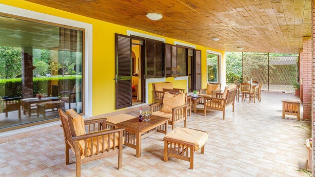 Un patio al aire libre con muebles de madera y una pared amarilla.
