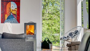 Ein modernes Wohnzimmer mit Kamin, Sofa, Sessel und einem Gemälde an der Wand.