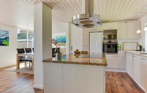 A modern kitchen with a central island, stainless steel appliances, and a dining area with a view of the outdoors. - Gorgeous home in Kruså with kitchen (Kruså)