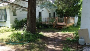 A wooden deck with a staircase leading to a house with green shutters. - Family and Friends 4 Bedroom Newer Vacation Home (Petoskey)