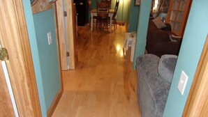 A hallway with wooden flooring leading to a dining area with a table and chairs. - Family and Friends 4 Bedroom Newer Vacation Home (Petoskey)