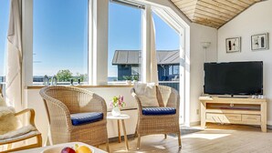 A bright room with wicker furniture, a TV, and a bowl of fruit. - 3 bedroom cozy home in Aabenraa (Aabenraa)