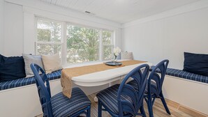 Un comedor con mesa, sillas y un banco con cojines.
