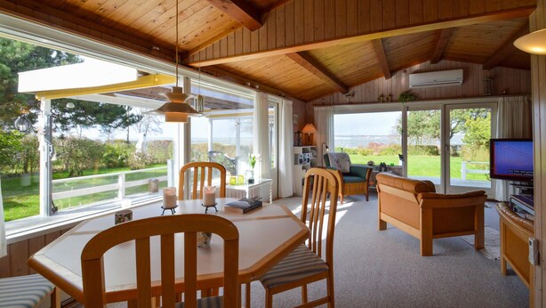 A cozy cabin interior with a dining area, a sofa, and a television. - Beach front home in Stubbekøbing (Stubbekøbing)
