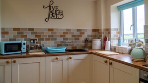 Une cuisine équipée d’un four à micro-ondes, d’un grille-pain, d’un évier et d’un panneau décoratif mural.