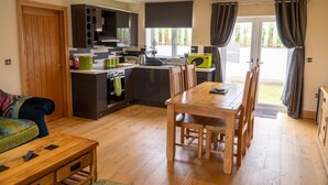 Een moderne keuken met een eethoek, houten meubels en een uitzicht door een glazen deur.