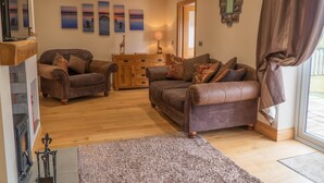 A cozy living room with two brown leather sofas, a wooden cabinet, and a fireplace. - Primrose Cottage -  2 Bed cottage with Hot Tub, walk to the beach. (Ulverston)