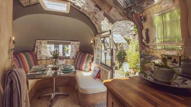 Interior acolhedor de uma RV com área de jantar, assentos e cozinha.