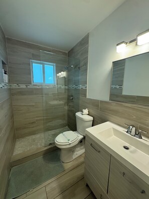 A modern bathroom with a glass-enclosed shower, a toilet, and a vanity with a sink. - Near Beaches downtown Renovated  large  3/2  one story  townhouse  "Casa Mango " (Miami)