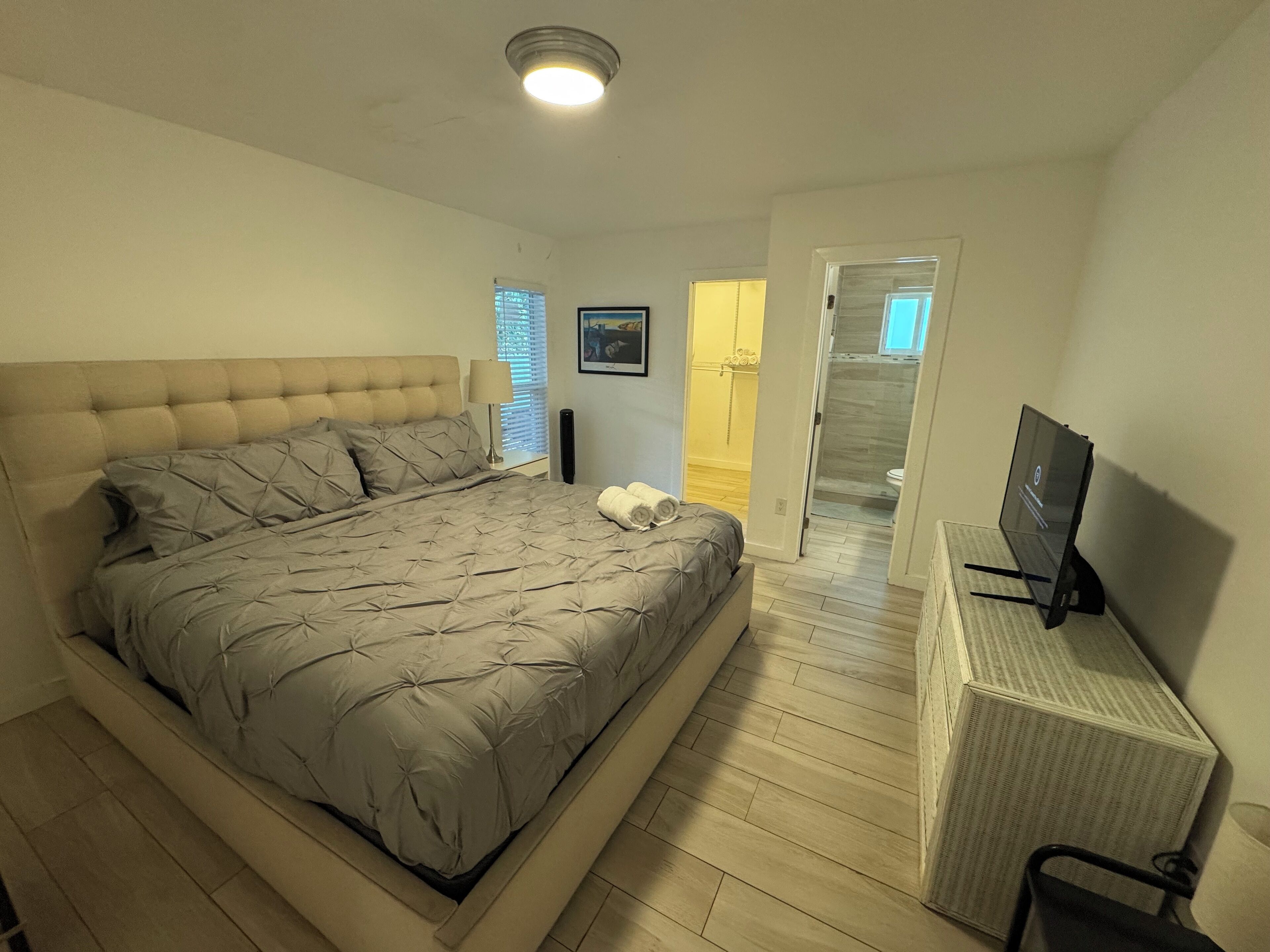 Ein Schlafzimmer mit einem großen Bett, einem Fernseher und einem begehbaren Kleiderschrank.