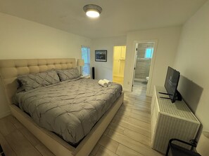 A bedroom with a large bed, a TV, and a walk-in closet. - Near Beaches downtown Renovated  large  3/2  one story  townhouse  "Casa Mango " (Miami)