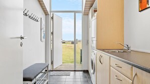 A modern kitchen with a built-in washing machine, a bench, and a view of the outdoors.