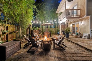 An outdoor patio with a fire pit, seating, and a wooden fence. - Casa DeSoto - Luxury Downtown Oasis (St. Augustine)