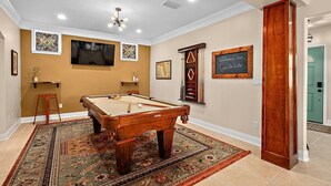 A pool table in a room with beige walls, a ceiling fan, and a welcome sign. - Casa DeSoto - Luxury Downtown Oasis (St. Augustine)