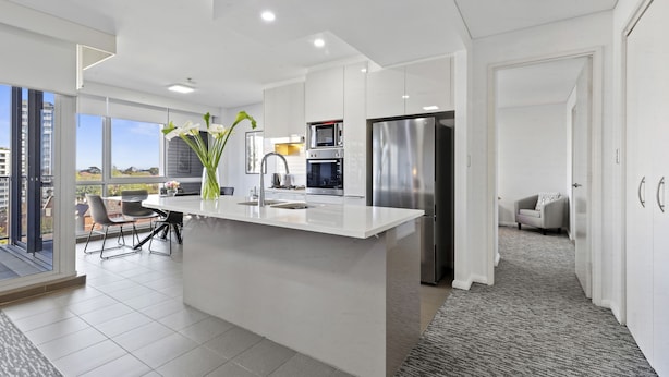Een moderne keuken met een centraal eiland, inbouwapparatuur en uitzicht op buiten.