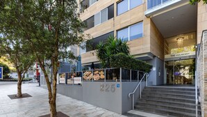 Een modern gebouw met een trap die leidt naar een ingang met de aanduiding '225'.